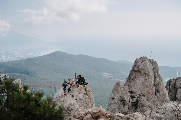 YALTA RUSSIA 8월 25일 2021 관광객들은 현수교에서 크림 반도의 AiPetri 산 절벽을 건너고 있습니다.
