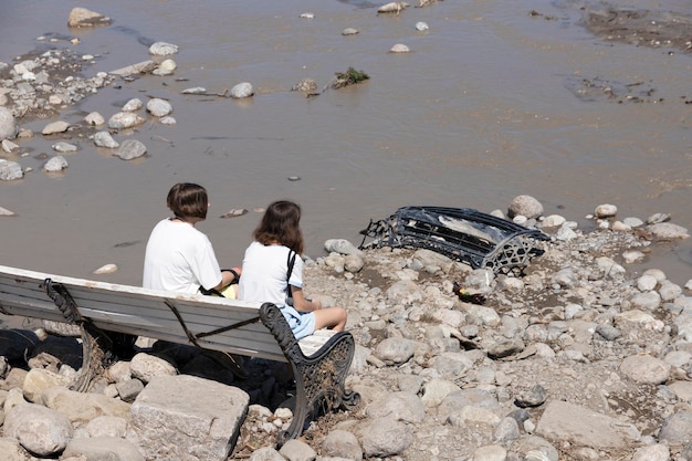 Yalta Ukraine July 26 2021 Two girls are sitting on a bench on the seashore and looking at the consequences of a natural disaster the consequences of a hurricane