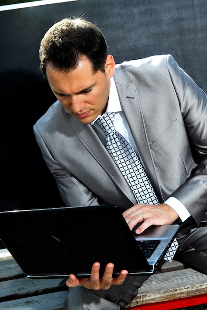 Yang businessman relaxing outdoors,dressed on suit.