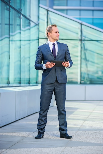 Yang businessman works with tablet computer outdoors.