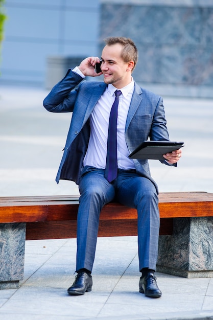 Yang businessman works with tablet computer outdoors.