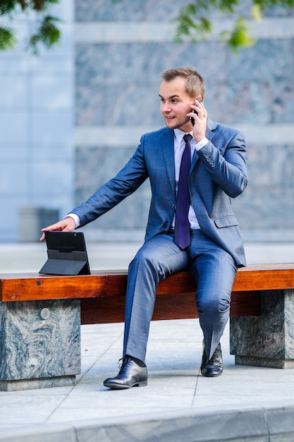 Yang businessman works with tablet computer outdoors.