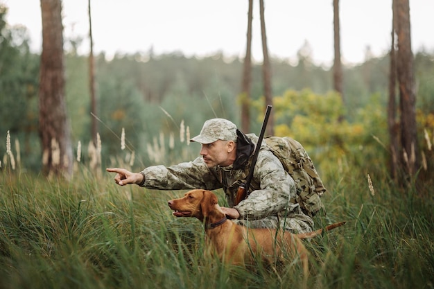 Photo yang hunter with rifle and dog in forest