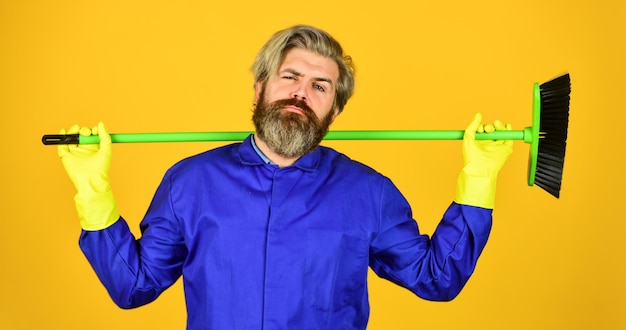 Foto yardman bezetting bebaarde hipster blauw uniform met bezem tuinman schoonmaak service man conciërge professioneel vuilnis verwijderen schoonmaakdag schoonmaakbureau werknemer met borstel schoonmaakapparatuur