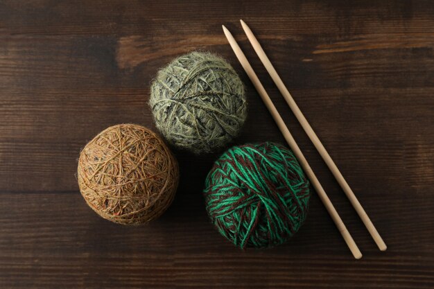 Yarn balls and knitting needles on wooden background