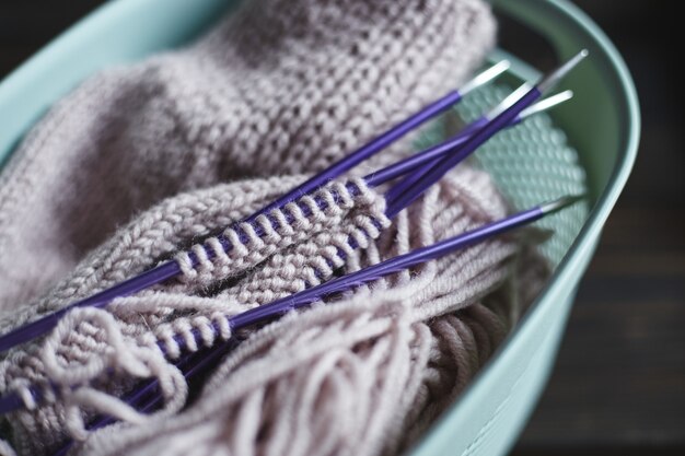 yarn in coils and knitting needles on wooden table. Home hobbies. Hand knitted sock with needles and yarn ball