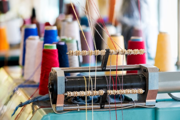 Фото Устройство подачи пряжи с нитками из шерсти разных цветов на вязальной машине на трикотажной фабрике крупным планом