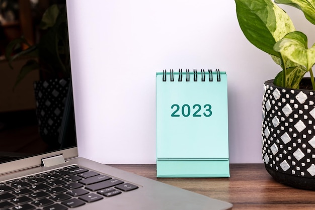 Year 2023 table calendar with laptop and plant