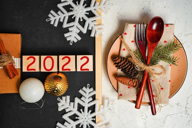 Year on a christmas background a plate with cutlery and christmas decorations snowflakes a gift and ...