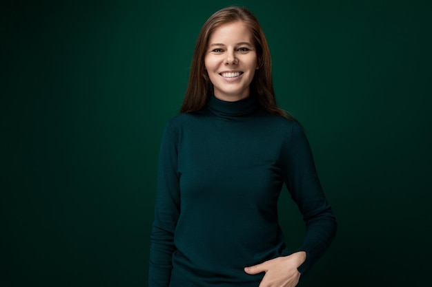 year old brownhaired european woman wearing a green turtleneck on a dark background