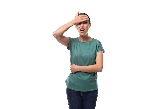 year old brunette woman with ponytail dressed in a green basic tshirt is worried and holding her