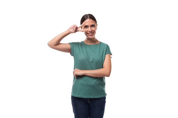 year old positive brunette woman with collected hair is dressed in a green basic tshirt on an