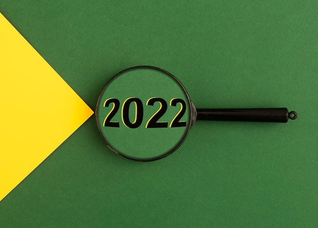 year through magnifying glass on green background with yellow light beam
