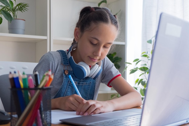 Photo a yearold girl in a gray tshirt uses headphones to study at the computer at home studies does