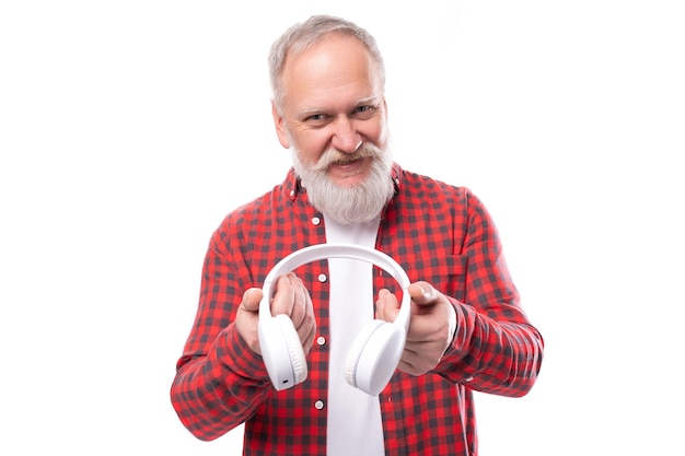 A yearold grayhaired pensioner man with a beard and mustache in a shirt listens to music on