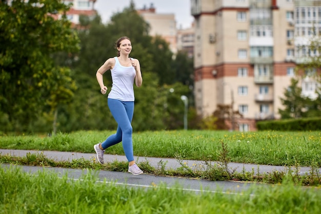 years old female runner jogging in a parked area of residential area with apartment buildings