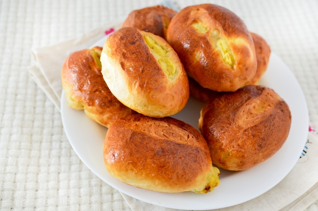 Yeast buns on white plate. pies with potatoes. delicious breakfast, homemade food. baking, dough.