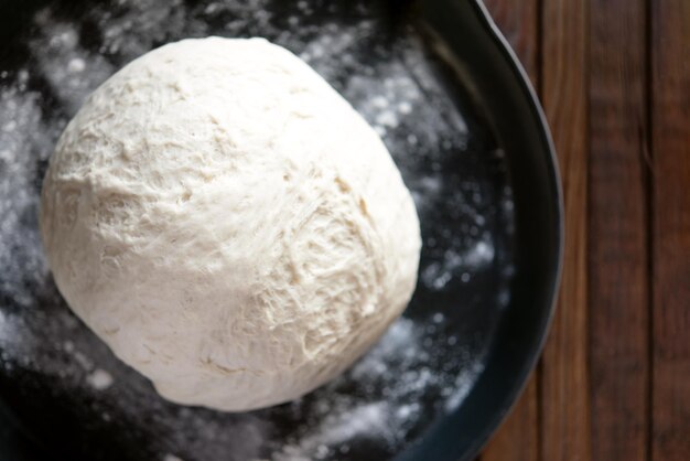 Yeast dough for bread or pizza on a floured surface with flour splash Cooking bread