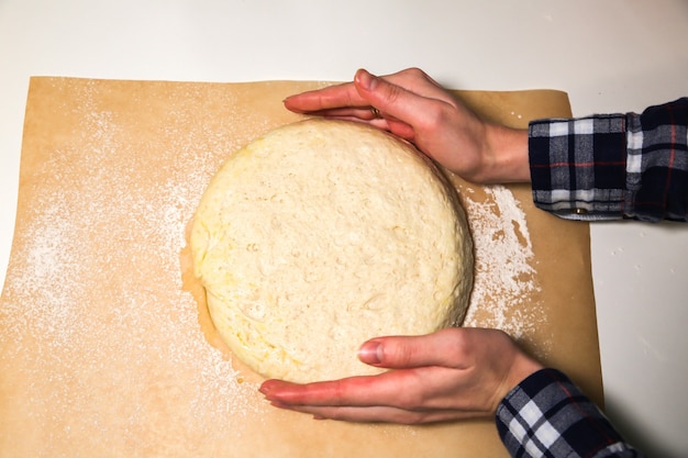 テーブルの上のイースト生地。ベーキングの概念。料理のアイデア。自家製料理を作る女性の手。小麦粉と水をこねます。