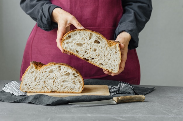 イーストフリーのサワードウパン美しいヨーロッパの女性パン屋が彼女の手にパンを持っています