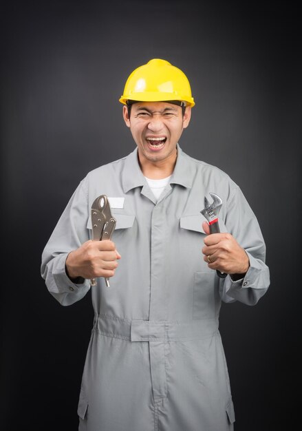 Yell young mechanic in suit with wrench