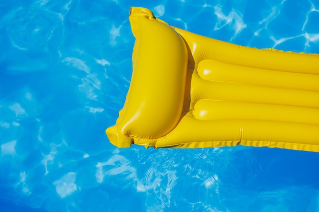 A yellow air mattress floats in an empty pool of blue water Summer holiday concept