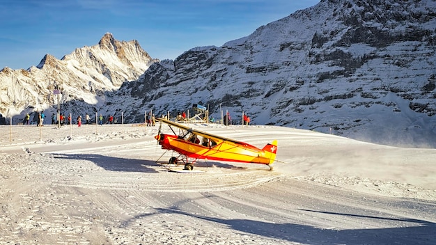 冬にスイスアルプスのアルペンリゾートに着陸する黄色い飛行機2