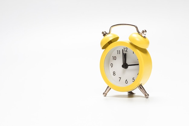 Yellow alarm clock isolated on a white wall.