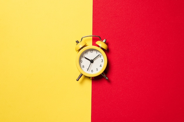 Yellow alarm clock on a yellow, blue, red and green background. Copy space. Time concept.