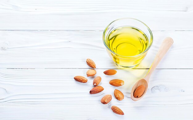 Yellow almond oil in a clear bowl with a wooden spoon next to it and several almonds on a white