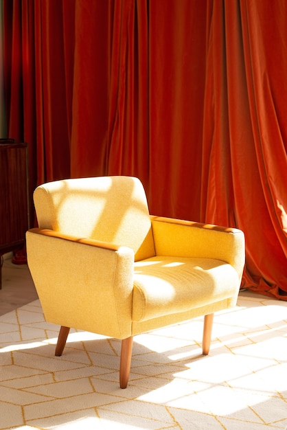 yellow armchair stands  on a carpet on the orange fabric wall background orange curtains with sunli