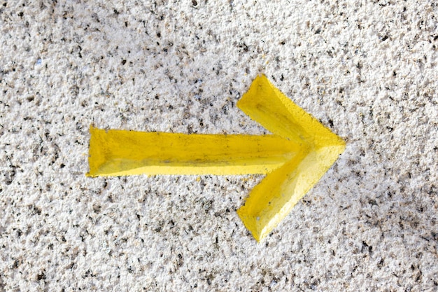 Photo yellow arrow chiseled on granite stone background