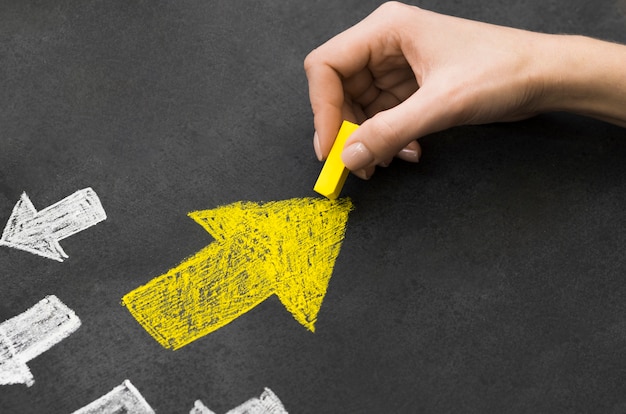 Yellow arrow in group of white arrows on black background