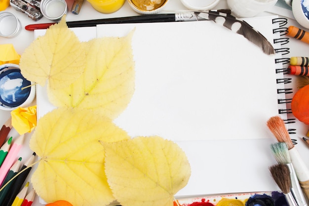 Photo yellow autumn leaves on blank sketchbook flat lay