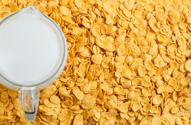 Foto sfondo giallo di corn flakes. il latte in una brocca. colazione salutare e nutriente. copia spazio