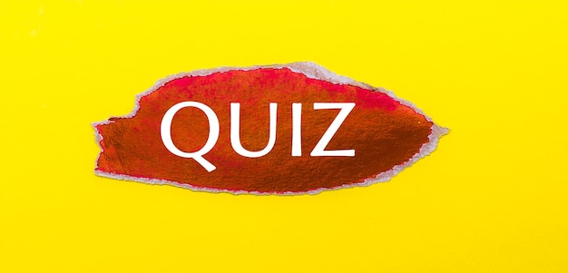 On a yellow background, a sheet of red paper with the word QUIZ