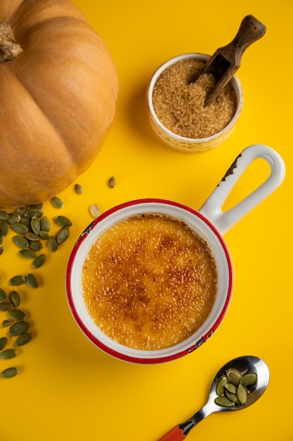 Yellow background and sweet pumpkin white bowl with food Male hand taking wooden spoon