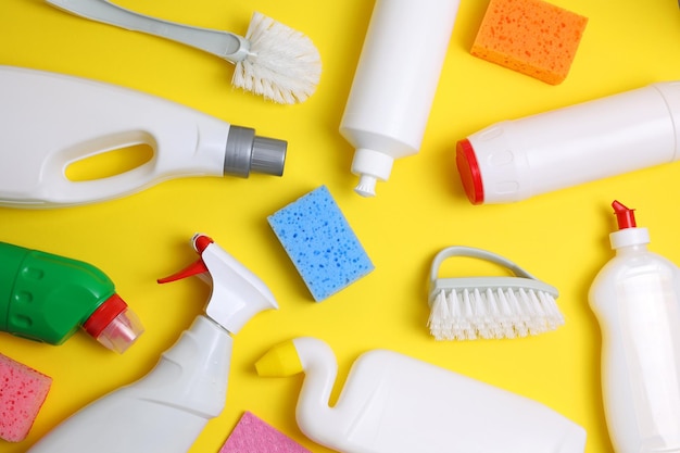 A yellow background with different cleaning products including a bottle of cleaner, a blue bottle and a white bottle of cleaner.