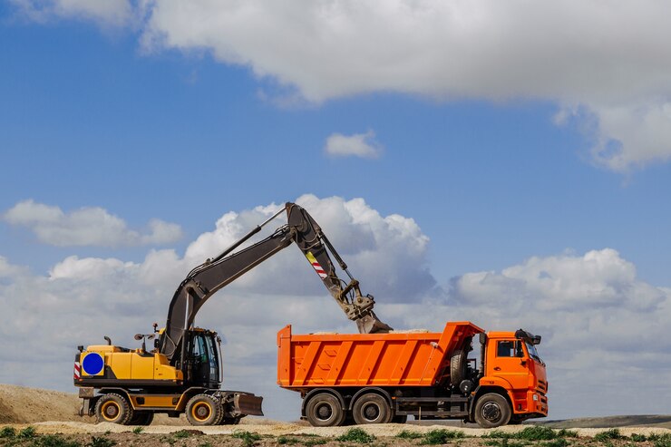 Photo a yellow backhoe loader loads the earth into a truck during the construction of a road.