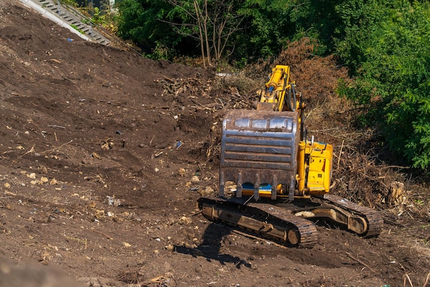 Yellow backhoe with hydraulic piston arm against clear blue sky\
heavy machine for excavation in construction site hydraulic\
machinery huge bulldozer heavy machine industry mechanical\
engineering