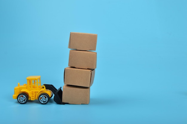 Yellow backhoe with paper boxes isolated on a blue background