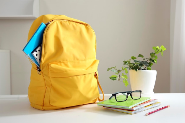 Фото Желтый рюкзак на столе. школьные принадлежности. вернуться к школьной концепции. объекты образовательного дизайна