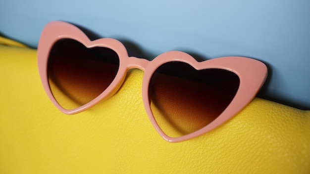 Yellow bag and heart-shaped sunglasses on blue background - summer picture