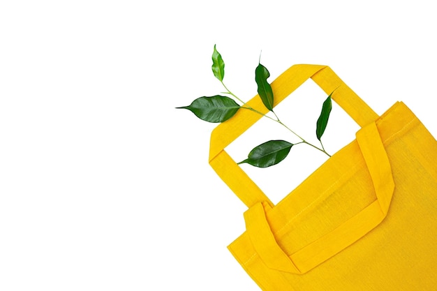 A yellow bag made of natural material and a green sprout isolated on a white background
