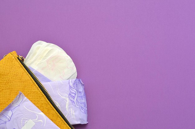 Yellow bag with feminine hygiene products on a purple background copy space