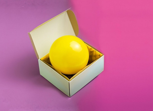 Yellow ball in boxgift or surprise conceptsfunny background