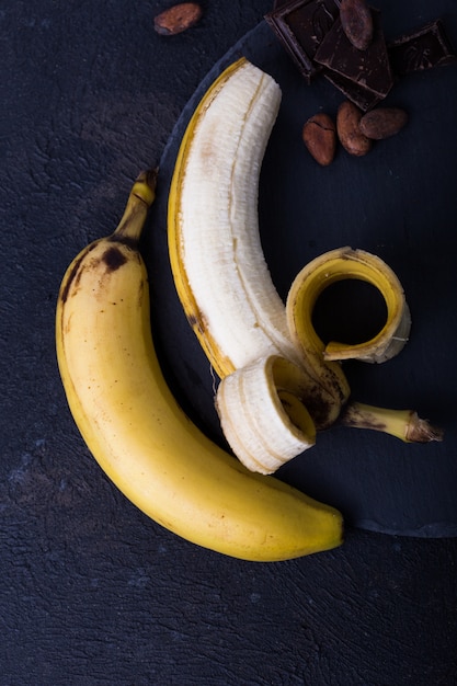 Yellow banan on black background. exotic food concept fruit\
minimal concept. flat lay.