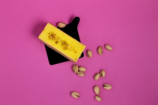 A yellow bar of soap with pistachios on a pink background