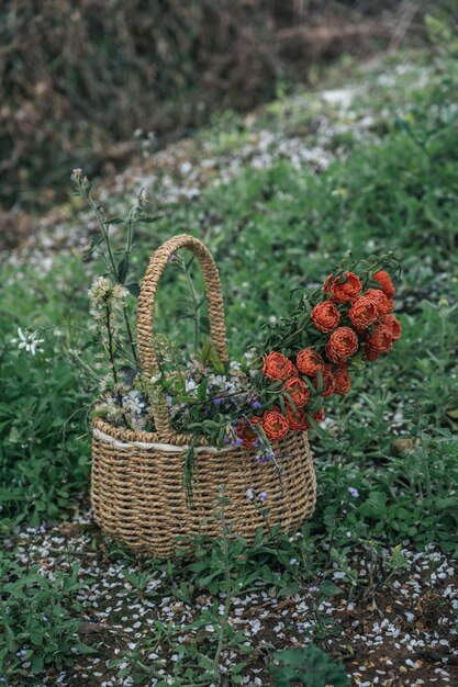 A yellow basket on the grass contains red flowers