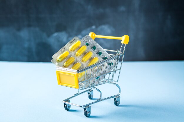 Yellow basket with pills on a blue surface